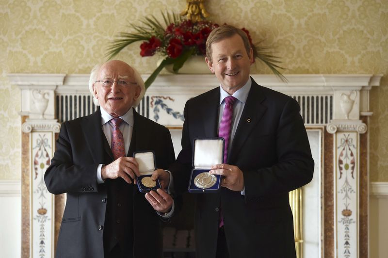 © Reuters. President Michael D. Higgins holds the holds the Seal of Taoiseach as Irish Prime Minister Enda Kenny holds the Seal of Government to office, in Dublin