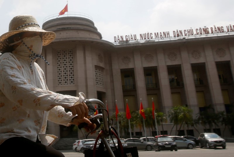© Reuters. A woman rides a bicycle past the building of the State Bank of Vietnam in Hanoi