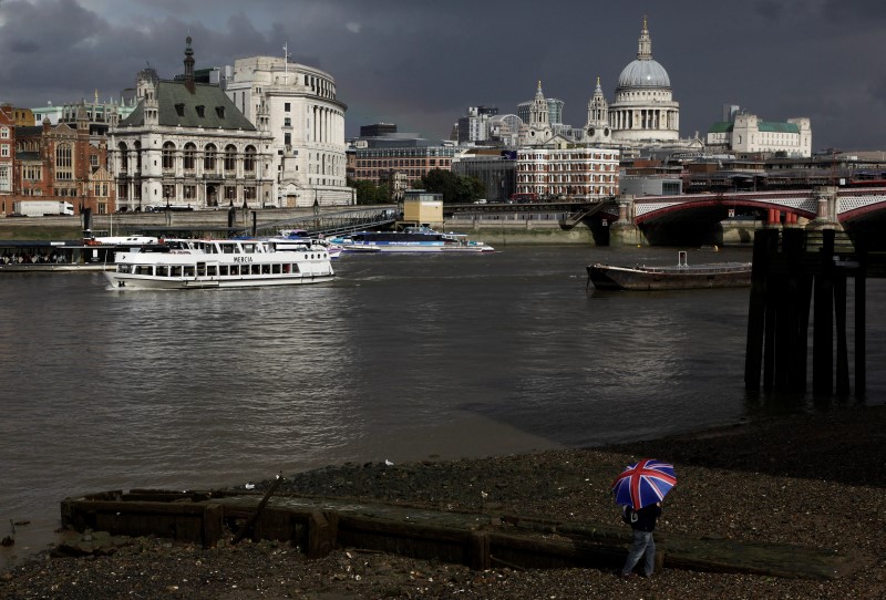 © Reuters. A man with an umbrella walks along the banks of the River Thames in central London