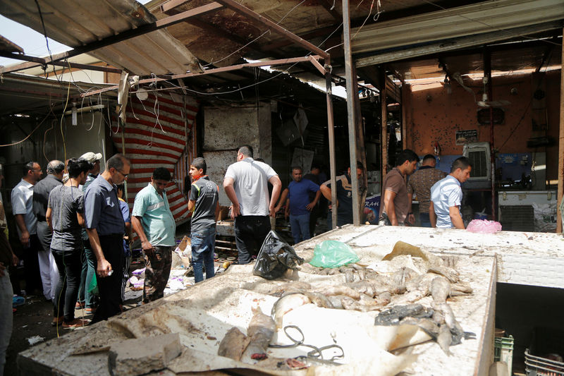 © Reuters. Pessoas vistas após explosão de bomba em mercado em Bagdá