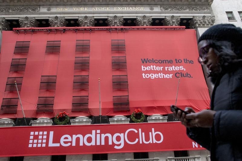 © Reuters. A woman looks at her phone as she passes by a Lending Club banner on the facade of the the New York Stock Exchange