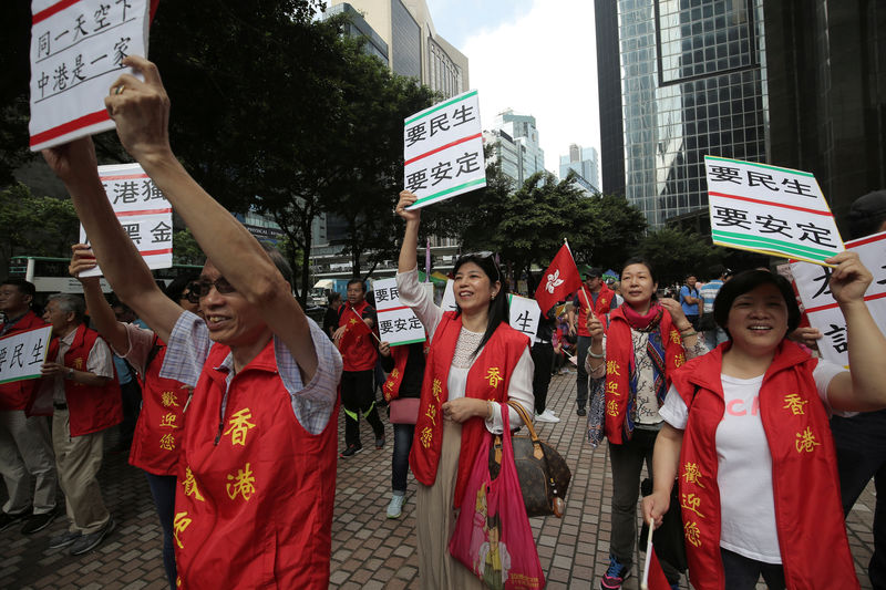 © Reuters. Supporters of visiting Zhang Dejiang, the chairman of China's National People's Congress, hold placards in Hong Kong