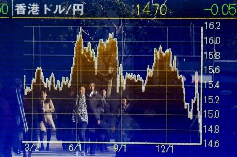 © Reuters. People are reflected in a display showing market indices outside a brokerage in Tokyo