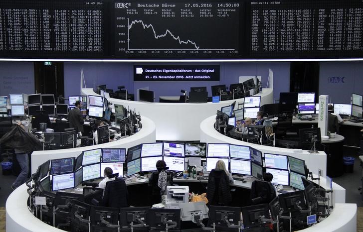 © Reuters. Traders work at their desks in front of DAX board at Frankfurt stock exchange