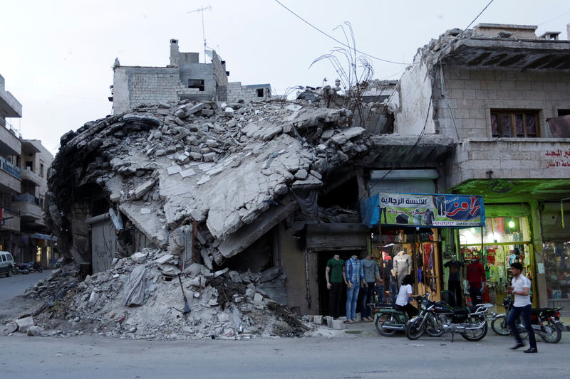 © Reuters. A clothing shop displays its merchandise beside a damaged building in the rebel-controlled area of Maaret al-Numan town in Idlib province