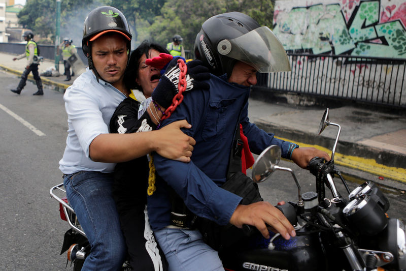 © Reuters. Opposition supporters affected by tear gas try to go out during a clash with riot policemen in a rally to demand a referendum to remove President Nicolas Maduro in Caracas