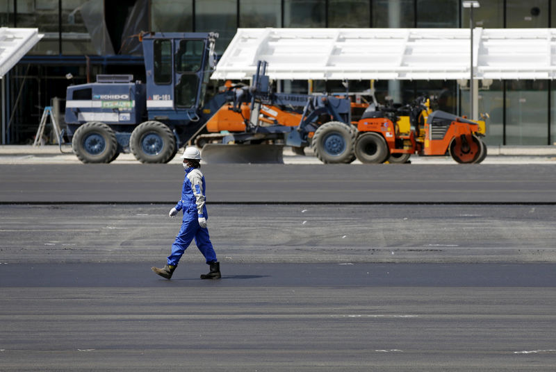 © Reuters. Worker walks in front of heavy machineries at a construction site in Tokyo