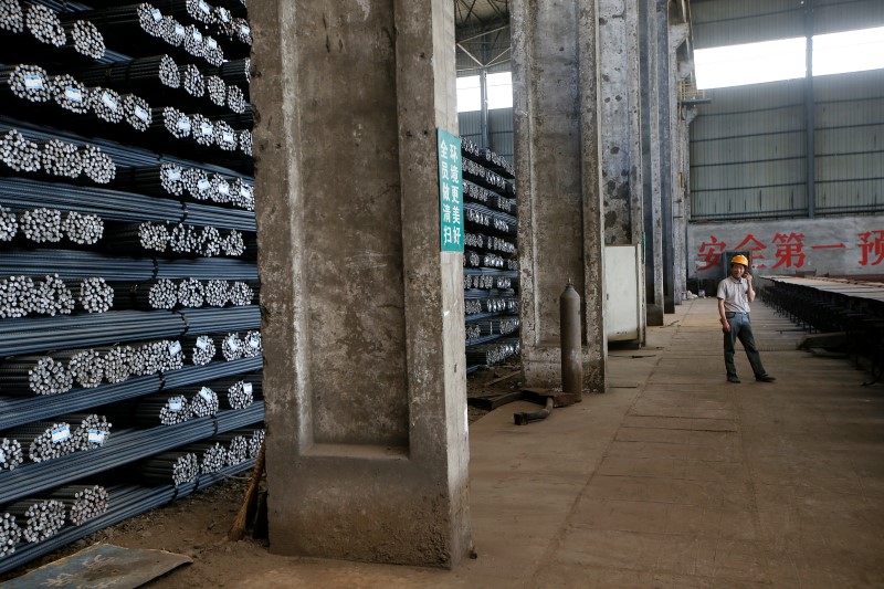 © Reuters. An employee talks on his mobile phone near stacks of rebar at Shanxi Zhongsheng Iron and Steel in Fenyang