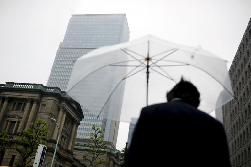 © Reuters. A businessman holds an umbrella as he stands near the Bank of Japan headquarters in Tokyo