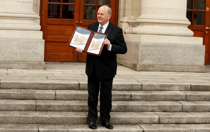 © Reuters. Ireland's Minister for Finance Michael Noonan displays a copy of the Budget on the steps of Government Buildings in Dublin