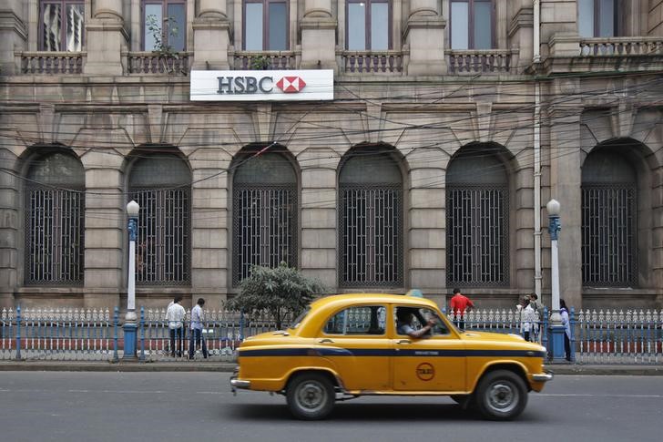 © Reuters. A yellow ambassador taxi drives past the HSBC bank building in Kolkata