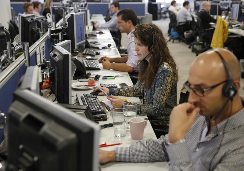 © Reuters. Traders sit at their desks at IG Index in London