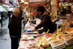 © Reuters. A shop clerk speaks to a shopper at a fish stall at a shopping district in Tokyo