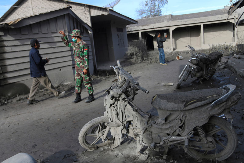 © Reuters. An Indonesian soldier helps others search an area following a deadly eruption of Mount Sinabung volcano in Gamber Village