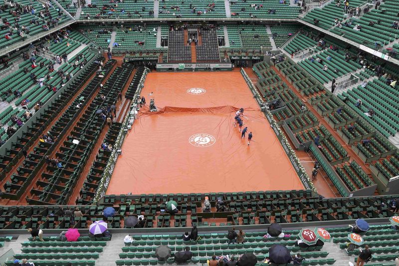 © Reuters. Tennis - French Open - Roland Garros - Court workers sweep away water