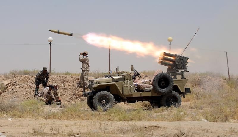 © Reuters. Miembros de las milicias paramilitares chiíes lanzan cohetes a militantes del Estado Islámico en las afueras de Faluya en Irak. Imagen de archivo