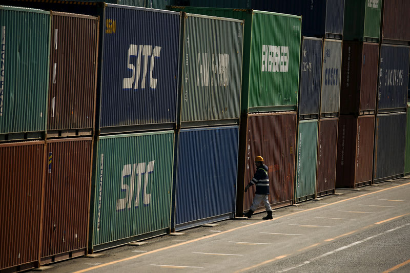 © Reuters. A worker walks between shipping containers at port in Tokyo