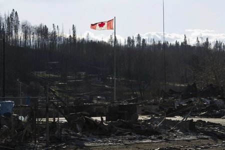© Reuters. A Canadian flag flies over damage caused by a wildfire in Fort McMurray