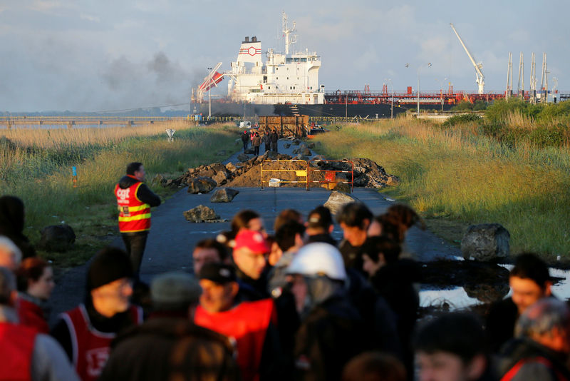 © Reuters. French workers and protesters walk near a barricade to block the entrance of the fuel depot of the society SFDM near the oil refinery of Donges