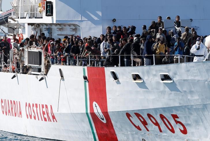 © Reuters. Migrants arrive by the Italian coastguard vessel Peluso in the Sicilian harbour of Augusta