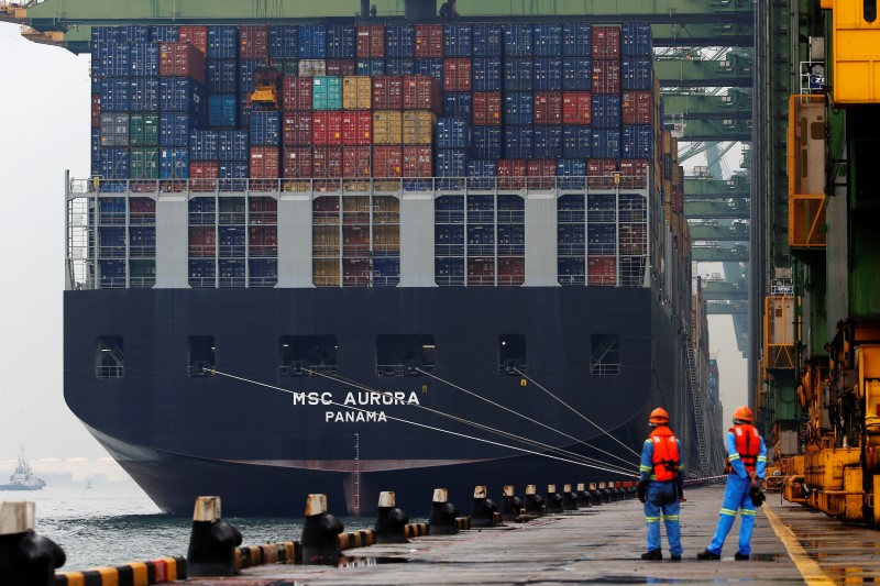 © Reuters. File photo of workers looking as a container ship is unloaded at a berth in a PSA International port terminal in Singapore