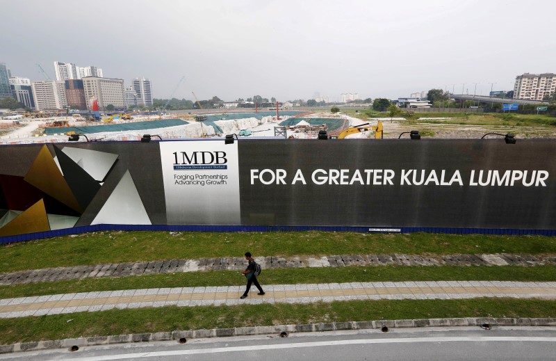 © Reuters. A man walks past a 1 Malaysia Development Berhad (1MDB) billboard at the funds flagship Tun Razak Exchange development in Kuala Lumpur