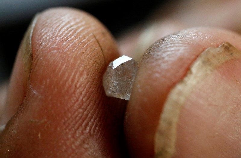 © Reuters. A diamond cutter shows a rough stone while working on it in his work place in Santa Elena de Uairen