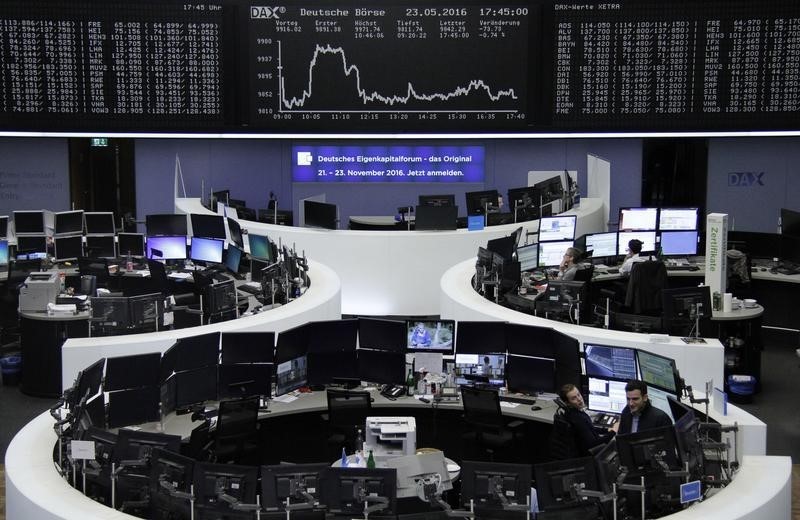 © Reuters. Traders work at their screens in front of the German share price index DAX board at the stock exchange in Frankfurt