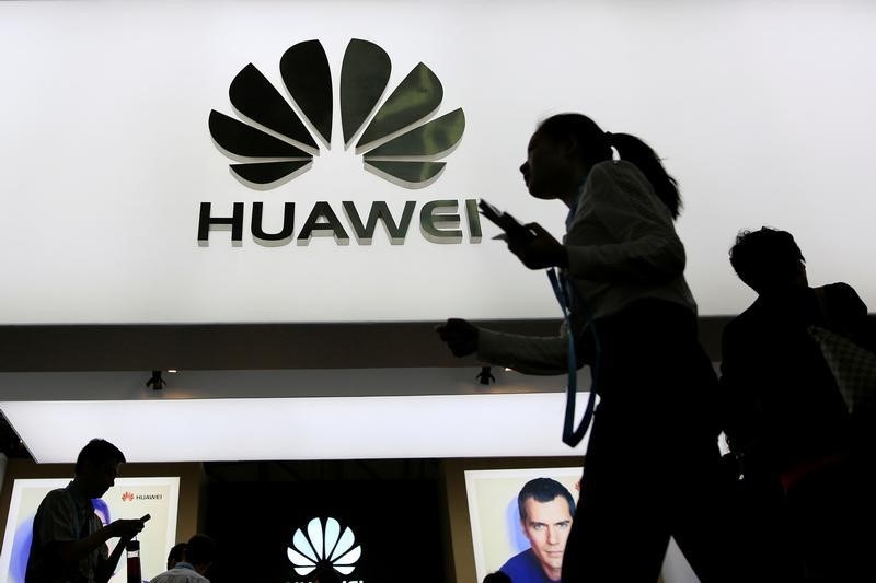 © Reuters. People walk past a sign board of Huawei at CES Asia 2016 in Shanghai