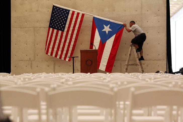 © Reuters. A worker takes off the U.S and Puerto Rican flag after a rally of U.S. Democratic presidential candidate Bernie Sanders in San Juan