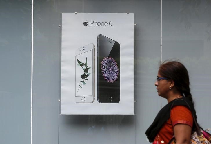 © Reuters. Mulher caminha em frente de anúncio com iPhone 6 em loja de eletrônicos em Mumbai, Índia