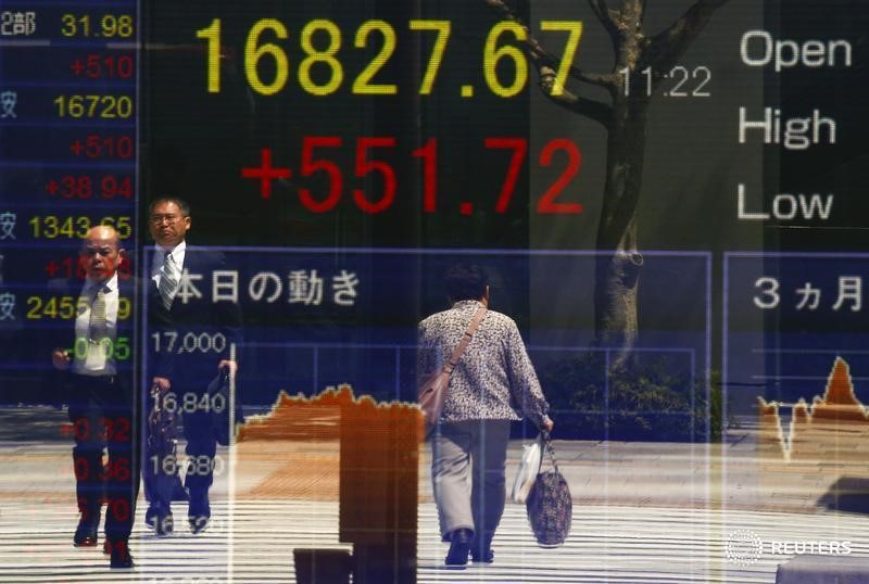 © Reuters. People are reflected in a screen displaying the Nikkei average outside a brokerage in Tokyo