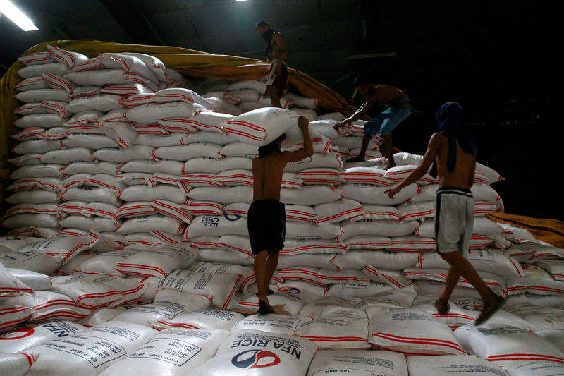 © Reuters. Workers work atop of sacks of imported rice piled inside a government warehouse of National Food Authority in Taguig city