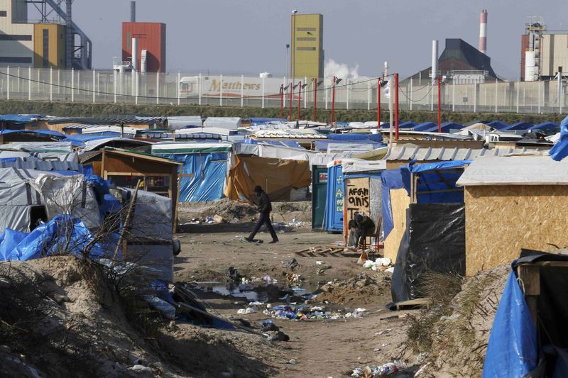 © Reuters. File photo shows a migrant walking past makeshift shelters in the northern area on the final day of the dismantlement of the southern part of the camp called the 'Jungle" in Calais