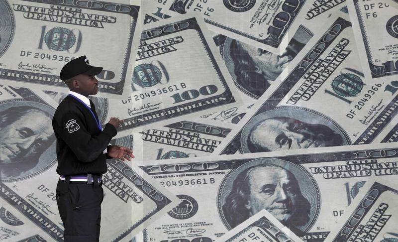 © Reuters. A security guard walks past a montage of U.S. $100 dollar bills outside a currency exchange bureau in Nairobi