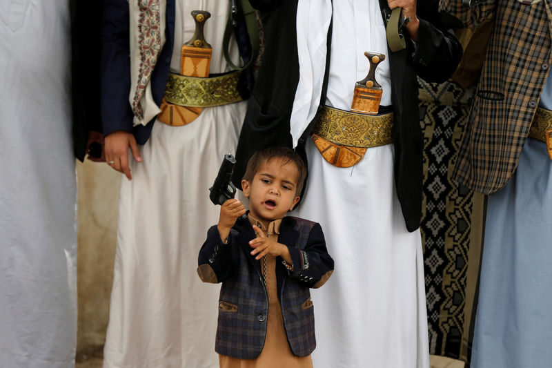 © Reuters. A boy holds his father's pistol as he attends with tribesmen loyal to the Houthi movement a gathering to show support to the movement in Sanaa, Yemen
