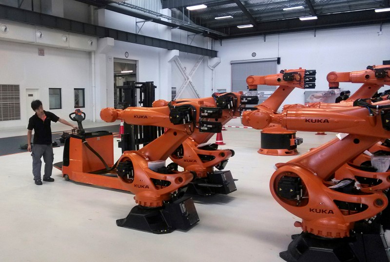 © Reuters. A staff member stands next to robots at a plant of Kuka Robotics in Shanghai