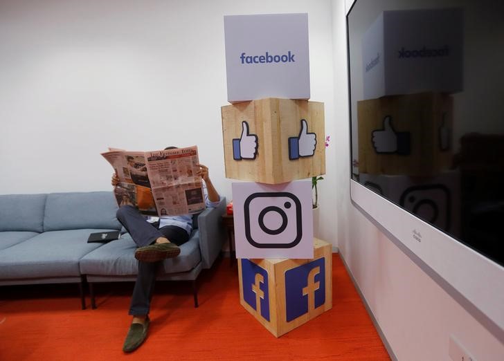 © Reuters. A man reads a newspaper at the reception area of Facebook's new office in Mumbai