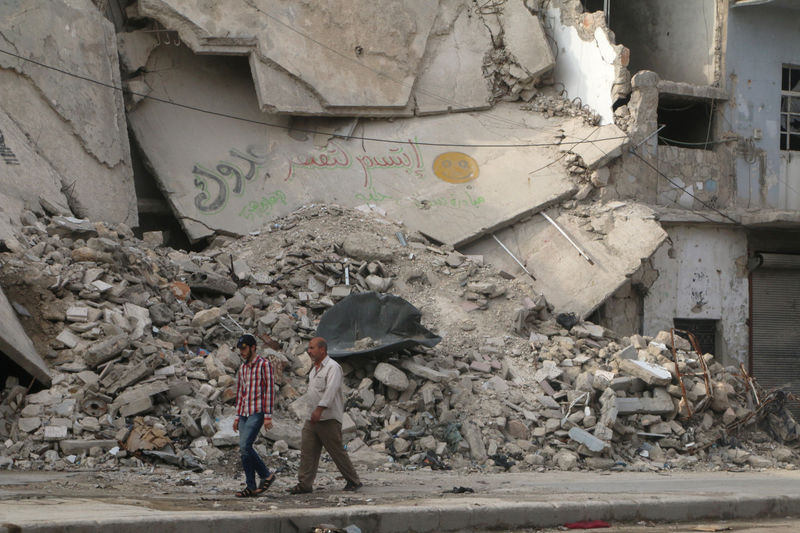 © Reuters. Men walk near a damaged building in Aleppo's rebel held al-Fardous district