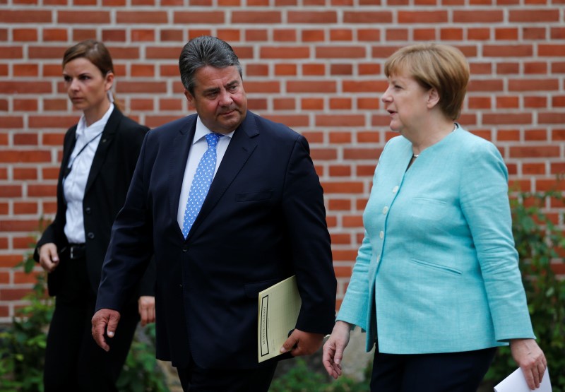 © Reuters. German Chancellor Merkel and Economy Minister Gabriel leave after a news conference at the German government guesthouse Meseberg Palace