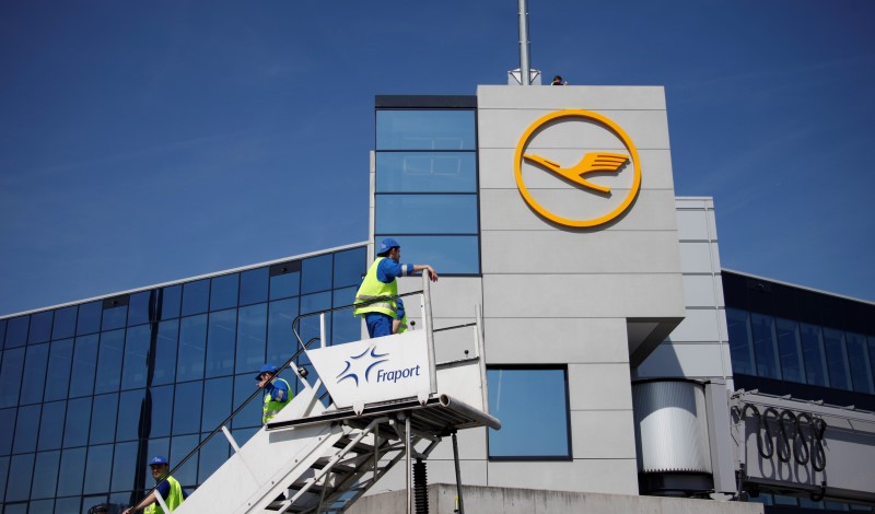 © Reuters. Ground staff of Frankfurt airport operator Fraport stand on a ladder in front a Lufthansa Logo at Frankfurt Airport