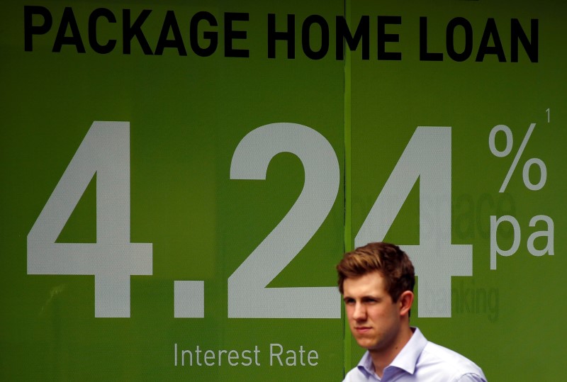 © Reuters. A pedestrian walks past an advertising billboard promoting home loan interest rates in Sydney, Australia