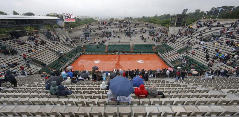 © Reuters. Tennis - French Open - Roland Garros - Spectators protect themselves from the rain