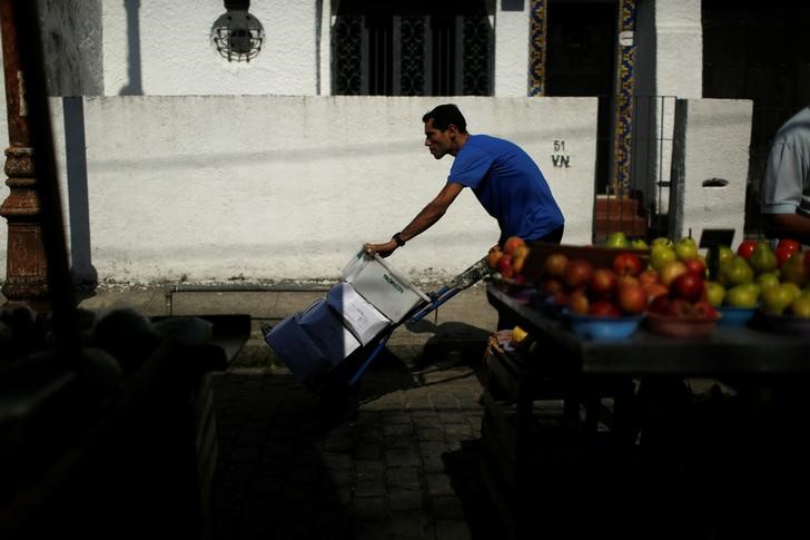 © Reuters. A worker pushes boxes with food at a street market in Rio de Janeiro