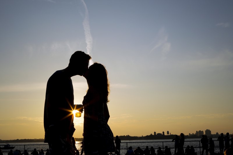 © Reuters. A couple kiss while they enjoy a sunny afternoon during the solstice day at Governors Island in New York, United States