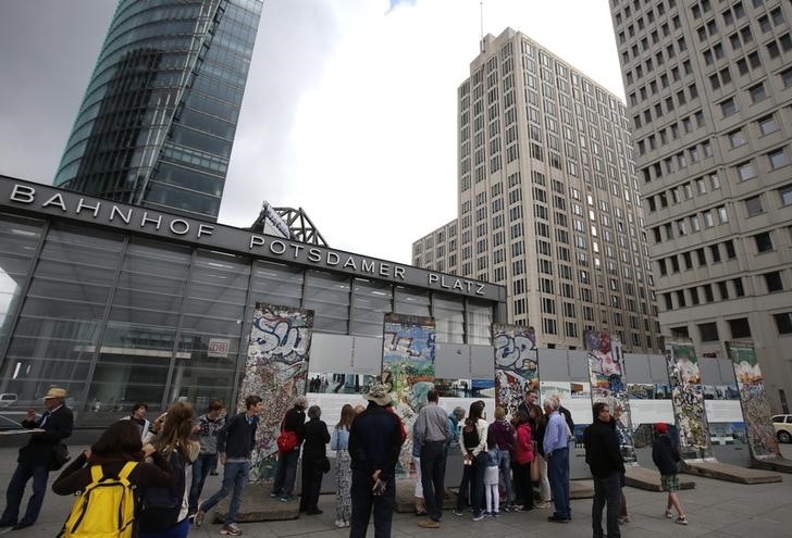 © Reuters. Tourists look at the remaining parts of the Berlin Wall placed in front of the Ritz Carlton Hotel, where U.S. President Obama will stay during his upcoming visit in Berlin