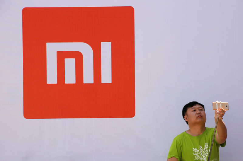 © Reuters. A man takes a selfie in front of the logo of Xiaomi at a venue for the launch ceremony of Xiaomi's new smart phone Mi Max in Beijing