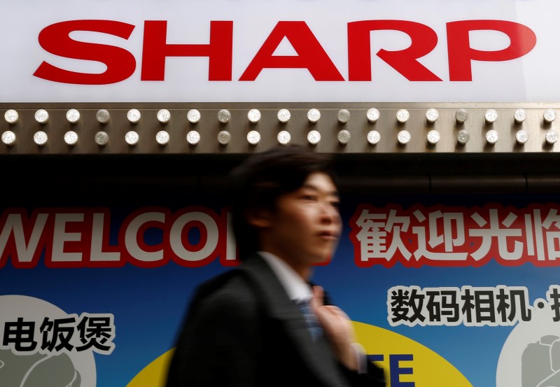 © Reuters. A logo of Sharp Corp is seen above a Chinese tourist standing outside an electronics retail store in Tokyo