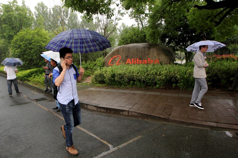 © Reuters. People walk past a sign of Alibaba Group at its campus in Hangzhou