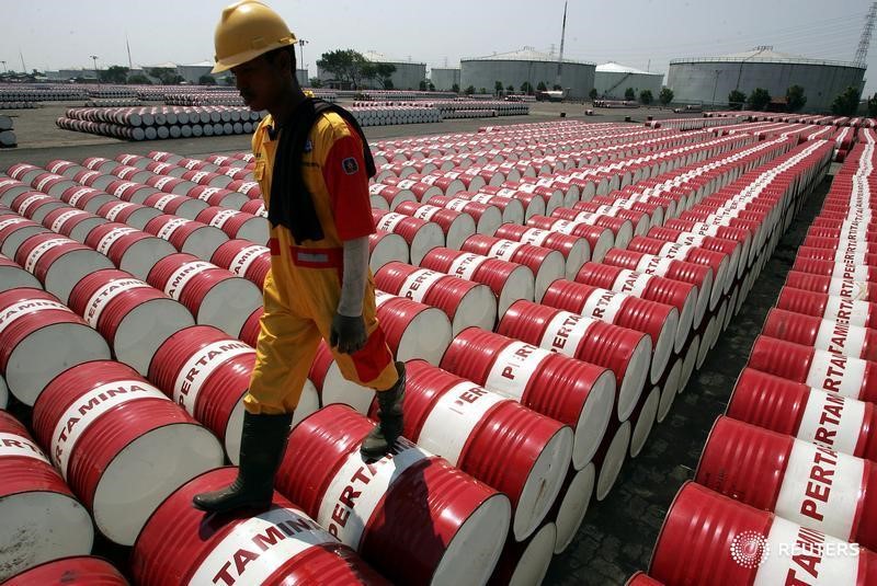 © Reuters. Employee of Indonesian oil company Pertamina walks on the top of drums at Jakarta's oil storage depot.